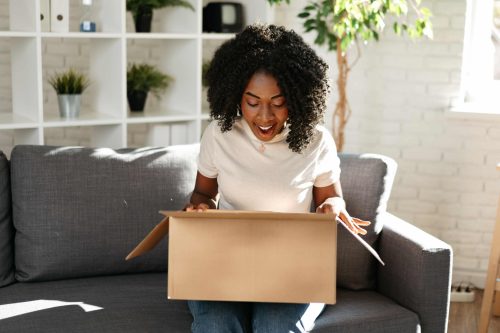 young-african-woman-sit-on-couch-at-home-unpacking-2022-12-10-01-12-24-utc-min